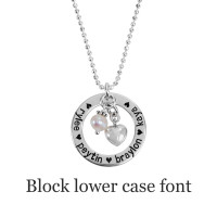 Hand stamped Mom Necklace in sterling silver with kids' names stamped in lower block font. Hung with pearl & silver puffed heart charm
