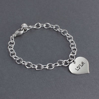 Side view of custom hand stamped silver heart bracelet, personalized with daughter's name, on a silver chain