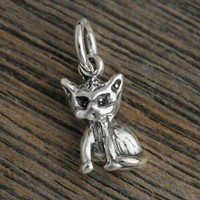 Sterling silver Little 3D Kitty Charm that can be added to a necklace or bracelet, shown on wood background