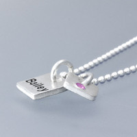 Side view of Fine silver Mini Squares personalized necklace, hand stamped with "bailey" and with an embedded birthstone