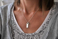 Model wearing personalized hand stamped Rectangle Warmth Necklace, with the silver rectangle charm hung on a ball chain