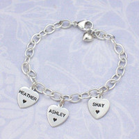 Custom silver heart charm bracelet, personalized with hand stamped names, shown with 3 charms and stamped hearts