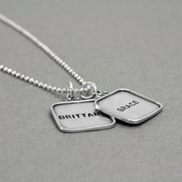 vintage style sterling silver hand stamped squares with raised edges, shown from the side on gray