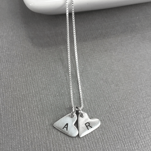 Custom sterling silver heart initial necklace, with 2 heart charms personalized with kids' initials A and R, shown from the top