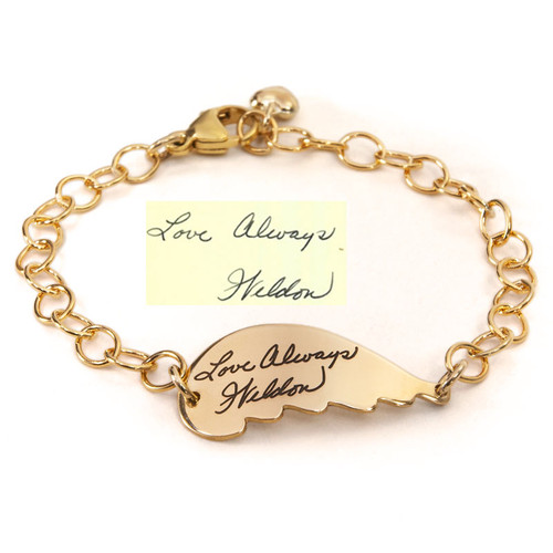 Gold handwriting memorial angel wing bracelet engraved with loved one's actual signature, shown with the handwritten salutation used to personalize it