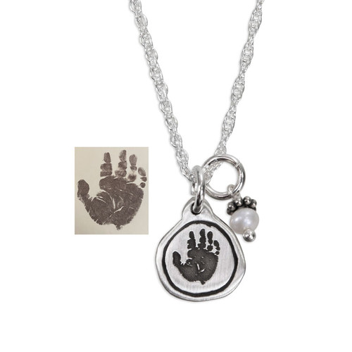 Custom sterling silver circle charm personalized with child's actual handprint, hung with child's birthstone, on a silver Dainty Cable chain, shown with the original handprint, on white