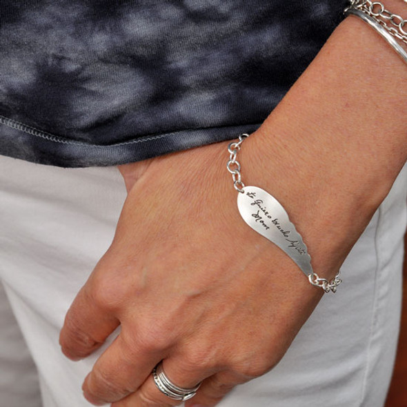 Model wearing Custom Memorial Silver Handwriting Angel Wing Bracelet, personalized with loved one's signature and handwritten note