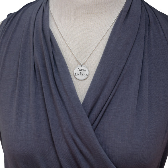 Model wearing custom silver handwriting disc necklace for mom personalized with actual handwritten signatures of her 2 children