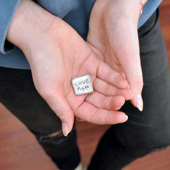 Hands holding Square Handwriting Pocket Token made from fine pewter. Token is hand-cast and designed to  an organic square with raised edges and your handwriting inscribed