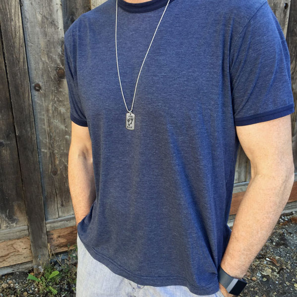 Male model wearing custom sterling silver military dog tag, personalized with baby's footprints, and stamped with name "Joel" and birthdate