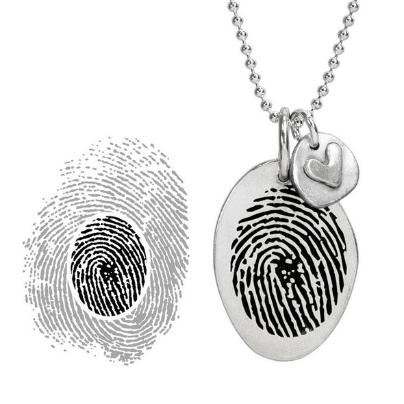 Custom silver fingerprint necklace, with silver heart charm, shown close up on white, with the section of the original fingerprint used to personalize the silver oval charm