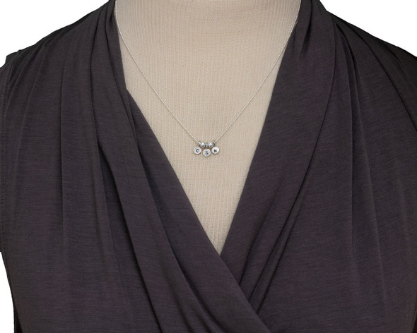 Our Tiniest Initials Necklace, custom made with sterling silver hand stamped charms, shown on a model