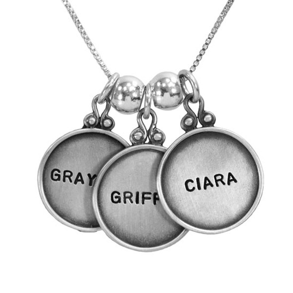 Personalized vintage style sterling silver circles with raised edges, hand stamped with kids names , shown close up on white