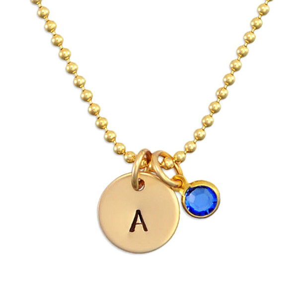 Custom Hand Stamped Gold initial birthstone necklace, personalized with child's initial & blue birthstone, shown close up on white 