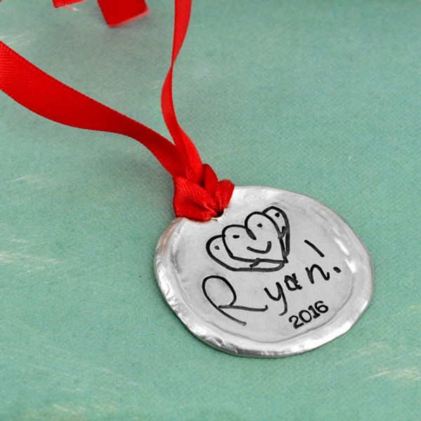 Custom fine pewter Christmas ornament, personalized with your child's artwork, shown close up on green