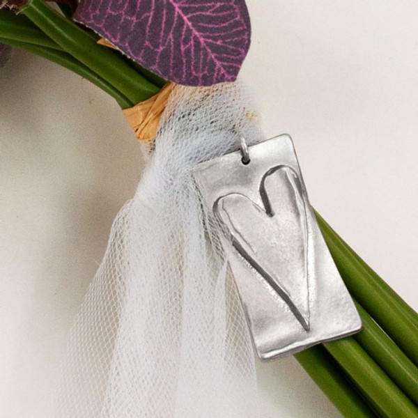 Close up of front of wedding bouquet charm showing raised heart