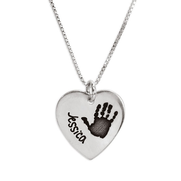 Child's actual handprint custom engraved on a silver heart charm personalized with stamped name "Jessica", shown close up on white