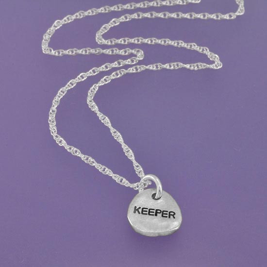 handmade silver circle charm with raised heart, showing stamping on back of charm