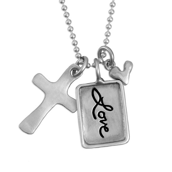 Silver charm with raised edge & the handwritten word Love, with a fine silver cross and fine silver heart, shown close up on white
