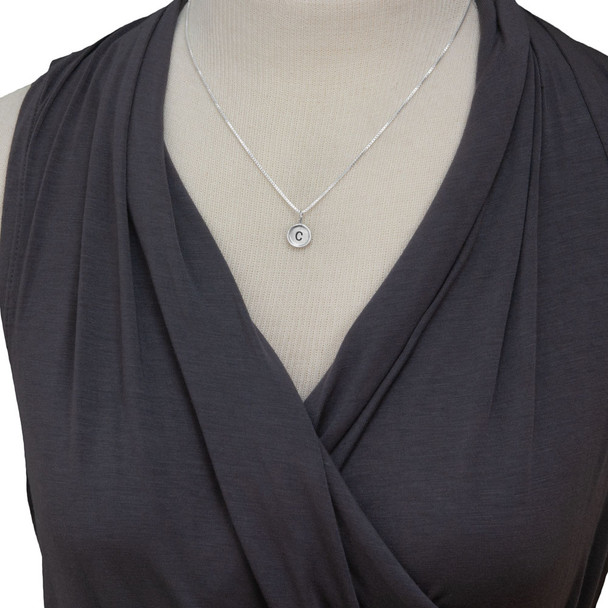 Model wearing custom mini round initial charms, handmade in sterling silver and personalized with hand stamped "C"