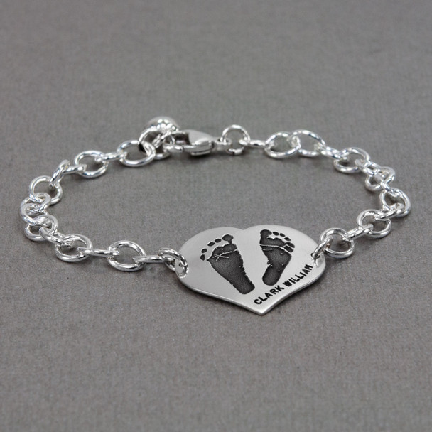 Custom silver heart bracelet personalized with your child's actual footprints, shown from the side