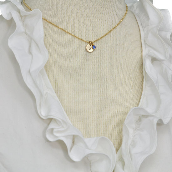Custom Hand Stamped Gold initial birthstone necklace, personalized with child's initial & blue birthstone, shown on model