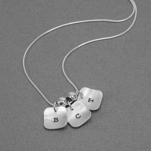 hand stamped brushed silver squares initial necklace, shown on gray