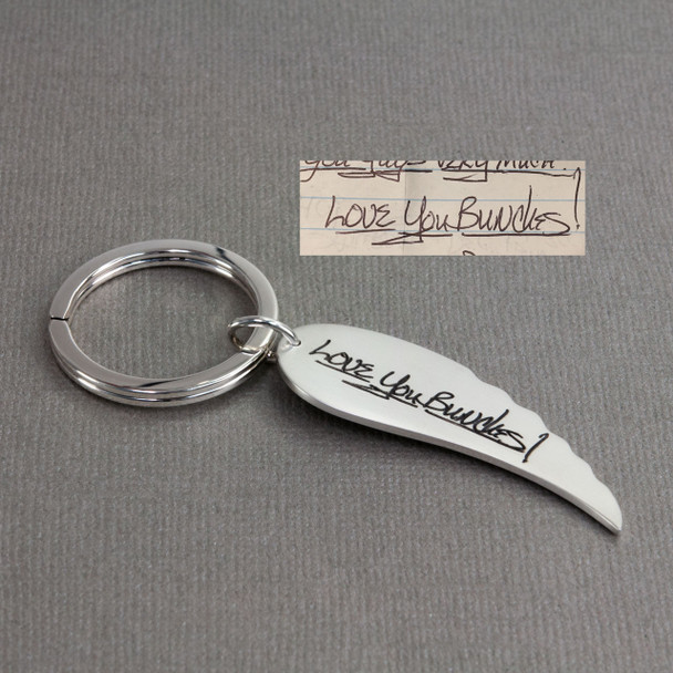 Personalized silver angel wing key ring with your loved one's handwriting, shown with the original handwritten note