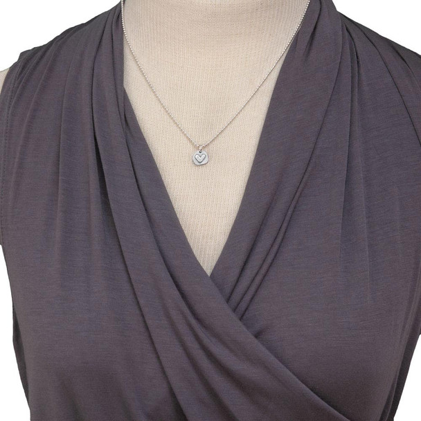 Handmade silver heart charm with stamping on back, shown on model