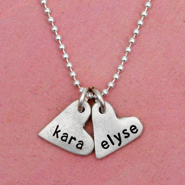 handcrafted silver heart charm necklace, hand stamped with names, shown up close