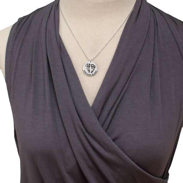 Sterling silver custom footprint necklace with your child's footprints, hand stamped with names and date, shown on a model