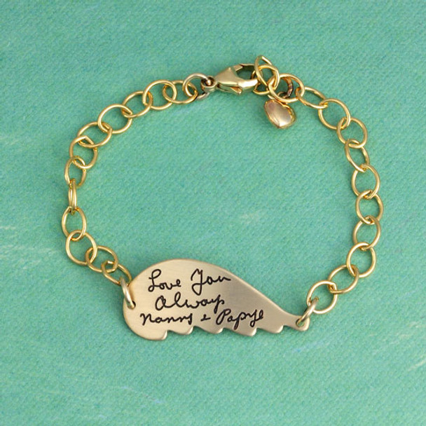 Gold memorial handwriting angel wing bracelet personalized with your loved ones actual handwriting, shown on green