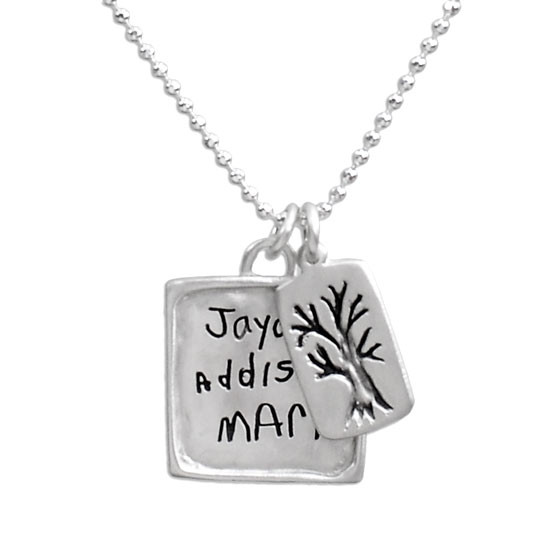 Close up view of handmade silver raised edge square pendant handwriting necklace, custom engraved with kids' handwritten signatures, and with silver family tree charm.