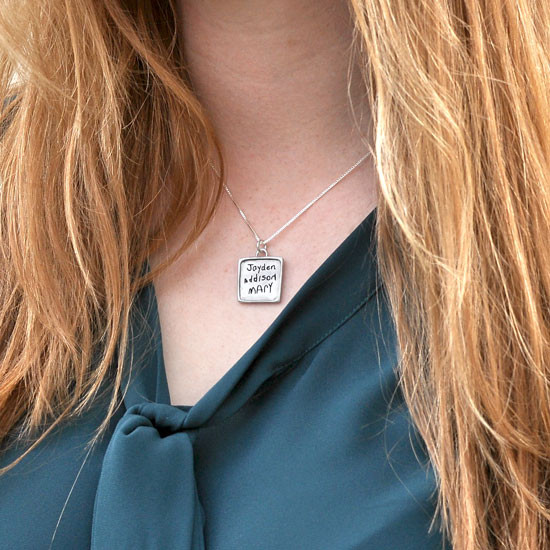 Model wearing handmade square pendant handwriting necklace, custom engraved with kids' handwritten signatures.