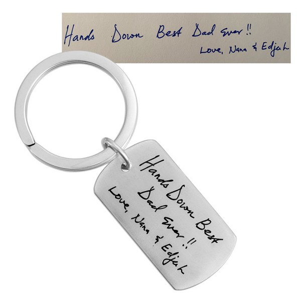 Back of custom silver key ring Father's Day gift with kids actual handwriting engraved on it, shown with the original handwritten note used to personalize it