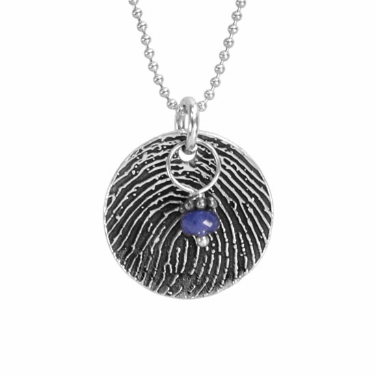 Custom sterling silver disc fingerprint necklace personalized with your actual fingerprint engraved on it, with a blue birthstone, viewed close up on white