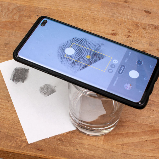 Using a water glass as a tripod for your mobile phone to take a clear, well-lit photo of your fingerprint.