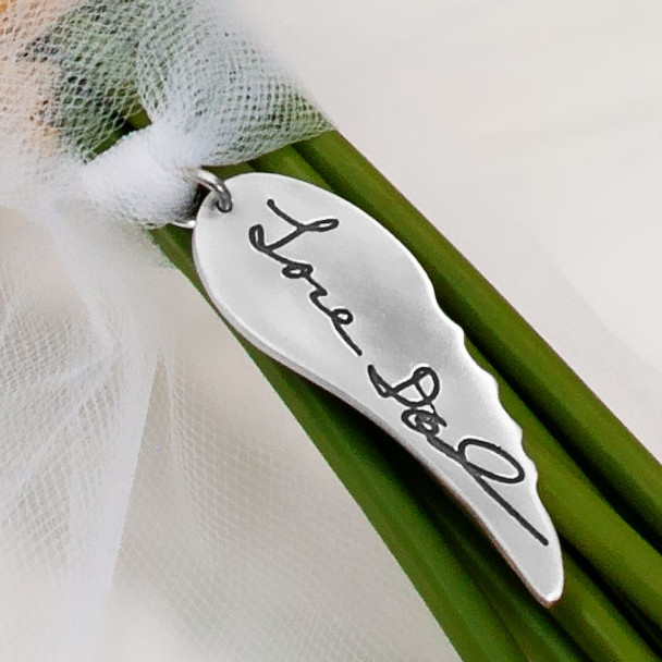 Memorial silver Angel wing bouquet charm engraved with actual handwritten signature from Dad, shown on bouquet