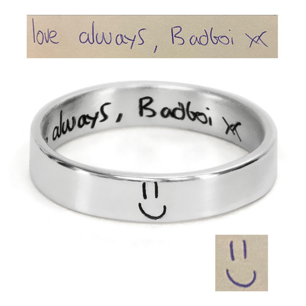 Custom Stackable Handwriting Ring, shown with original handwritten note from husband used to personalize it, on a white background. The inside of the ring has a hidden message: "Love Always" and a signature. The outside has a his hand drawn smiley face.