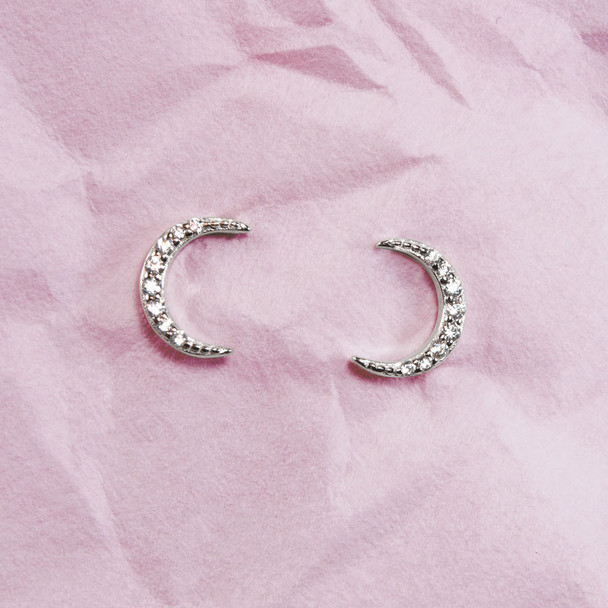 Sparkly silver moon earrings, with cubic zirconia stones, shown on pink background