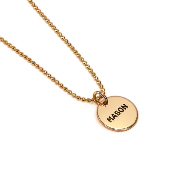 Hand stamped custom Gold Name Discs necklace personalized with kid's name, shown from the side on white