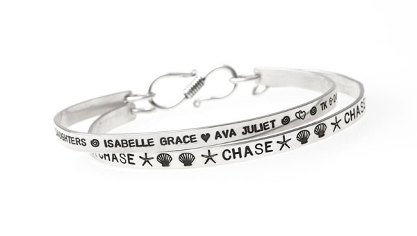 Personalized sterling silver bracelets, hand stamped with kids' names and symbols, shown on white