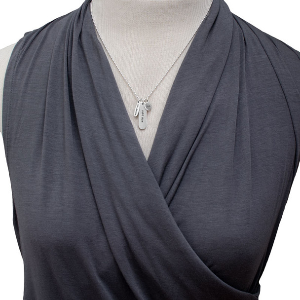 Model wearing custom silver Marathon Necklace with charms showing marathons she's run, dates & distances, and a large silver tag stamped with, "Just Run"