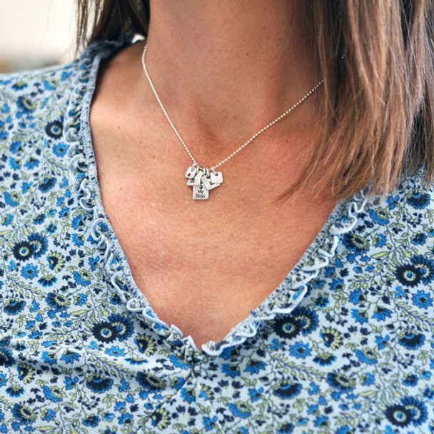 Model wearing fine silver Mini Squares personalized necklace, each square hand stamped with a name and with an embedded birthstone
