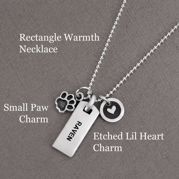 Custom silver Rectangle Warmth Necklace, stamped with pet's name Raven, shown with Silver Etched Lil Heart Charm and silver Small Paw Charm on a silver ball chain