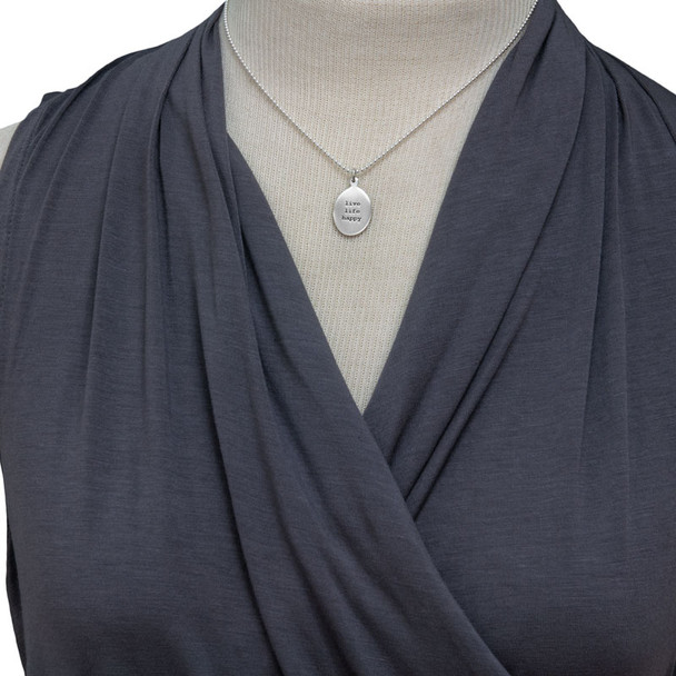 Model wearing custom sterling silver oval charm necklace, personalized with stamped inspirational phrase using Typewriter Lower Case font