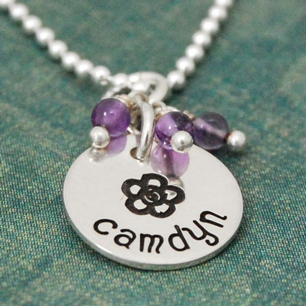 Side view of Custom sterling silver disc with stone cluster, personalized with hand stamped flower & child's name