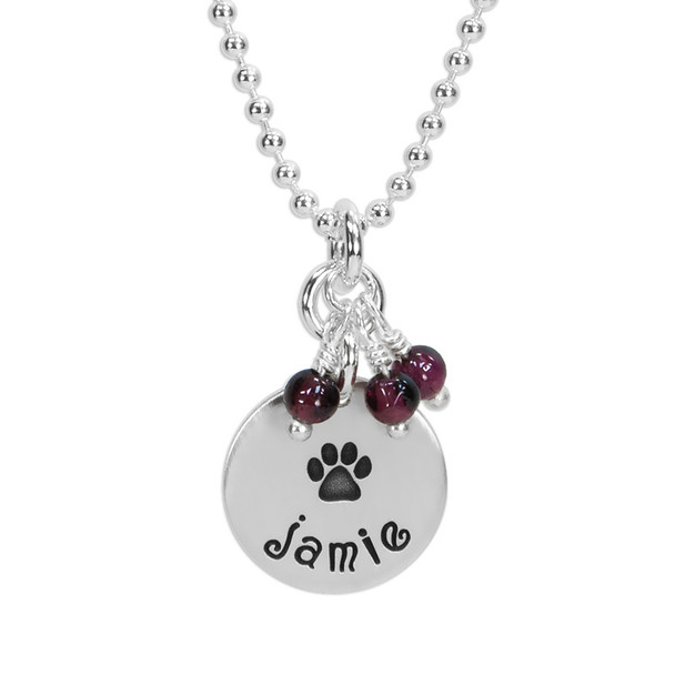 Custom sterling silver disc with stone cluster, personalized with hand stamped dog's paw & name, and amethyst stones. Shown close up on white.