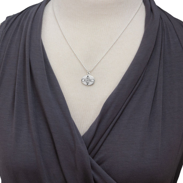 Model wearing silver Sweet Frame oval charm necklace personalized with daughter's name stamped in the middle.