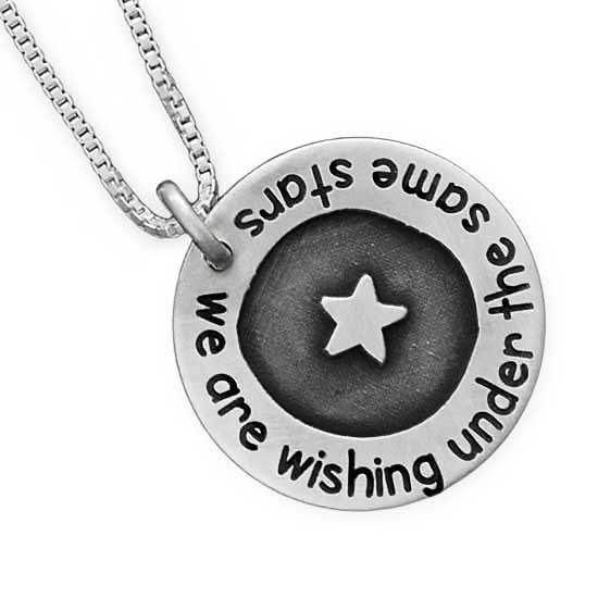Silver Under the Stars Necklace, with a star in the middle in raised relief, and "We are wishing under the same stars", shown close up